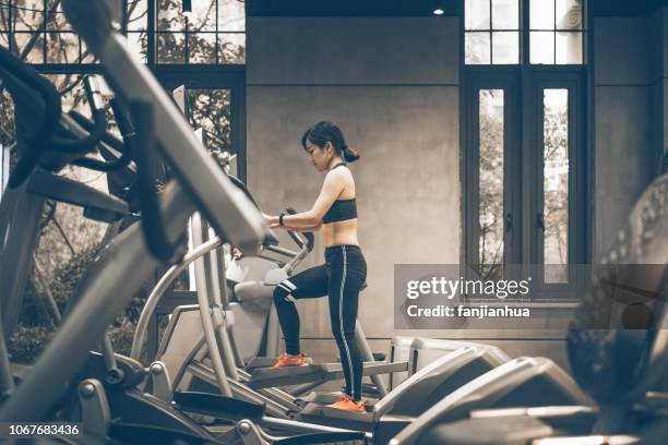 young woman exercising on a cross trainer - cross trainer stock-fotos und bilder