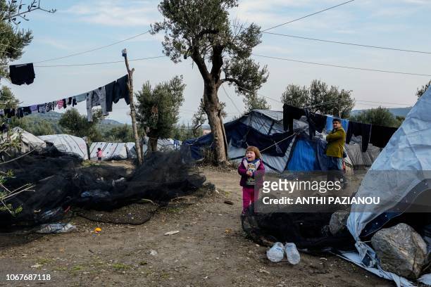 Child stands next a tent at a makeshift camp adjacent to the Moria camp for refugees and migrants on the island of Lesbos, on December 2, 2018. - The...