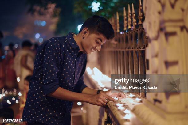 teenager boy lighting lamp during diwali festival - india diwali lights stock-fotos und bilder