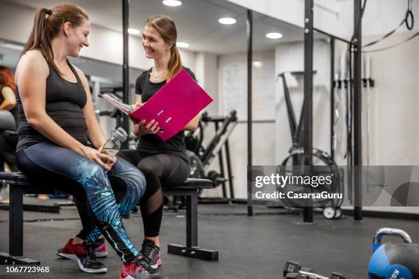 female fitness instructor going thru written training program with her client - fitness personal trainer imagens e fotografias de stock