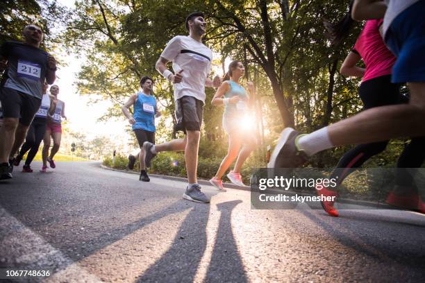 below view of athletes running a marathon on a road in nature. - road running stock pictures, royalty-free photos & images