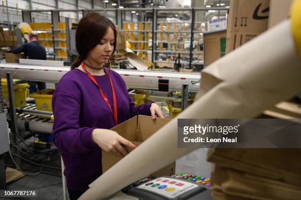 Member of staff packs customer orders in the packing area at the Amazon Fulfillment Centre on November 14, 2018 in Hemel Hempstead, England. The...