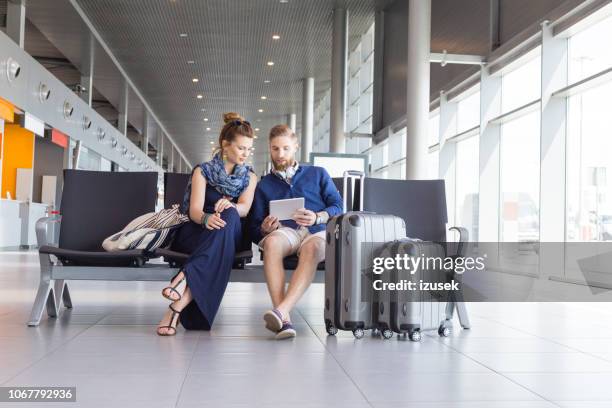 young couple waiting for flight in airport lounge - bored girlfriend stock pictures, royalty-free photos & images