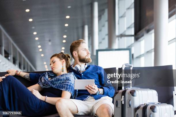 junges paar warten auf flug im flughafen-lounge - jetlag stock-fotos und bilder