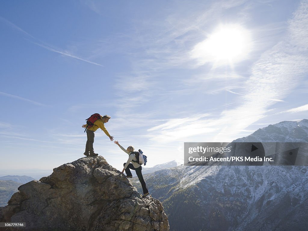 Hiker extends helping hand to teammate, on ridge