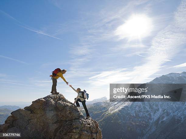hiker extends helping hand to teammate, on ridge - reaching summit stock pictures, royalty-free photos & images