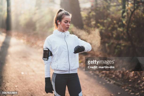 sportvrouw pols na sport activiteit controleren - zichtbare adem stockfoto's en -beelden