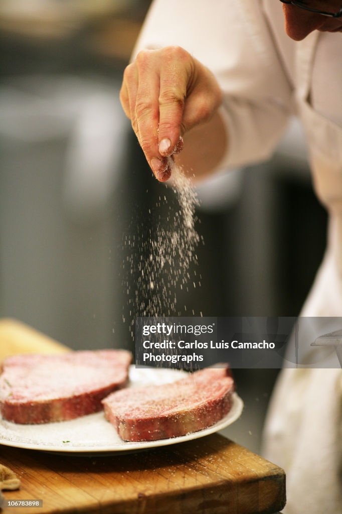 Chef salting steaks
