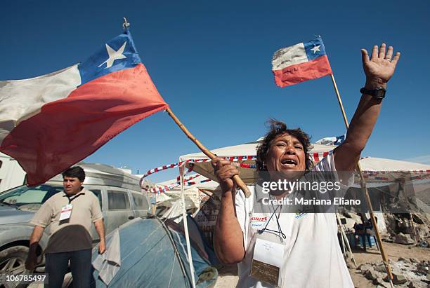 Relative of a trapped miner waves and shouts with a Chilean flag as trucks pass by Campamento Esperanza, transporting materials for the rescue of...