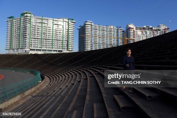 Cambodian woman walks for a morning exercise at the National Olympic Stadium in Phnom Penh surrounded by high rise building constructions on December...