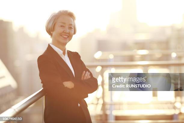 mature businesswoman smiling on rooftop - grey hair cool woman stock-fotos und bilder
