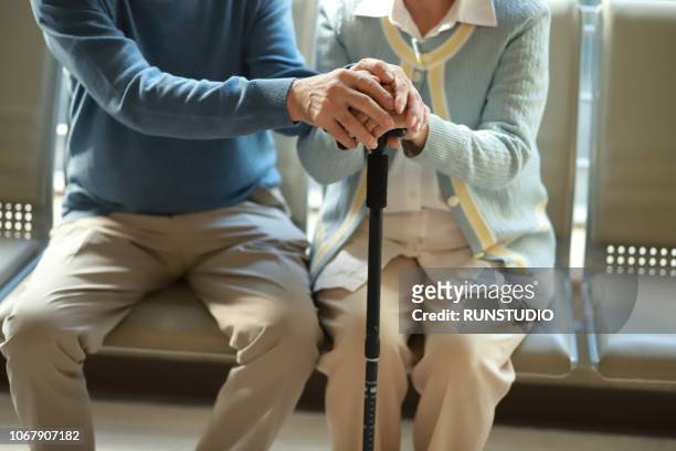 senior couple holding hands with walking cane - spazierstock stock-fotos und bilder