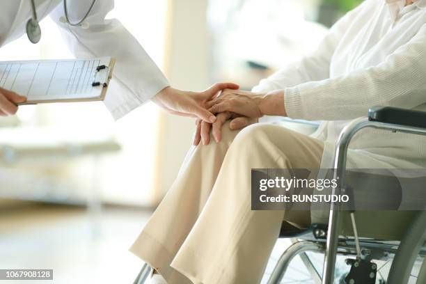 doctor examining patient in wheelchair - japanese old man stock-fotos und bilder