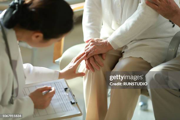 doctor checking patient's knee pain - elder couple asian stock-fotos und bilder