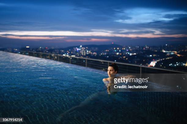 young woman having a night swim in the pool in malaysia - upper class stock pictures, royalty-free photos & images