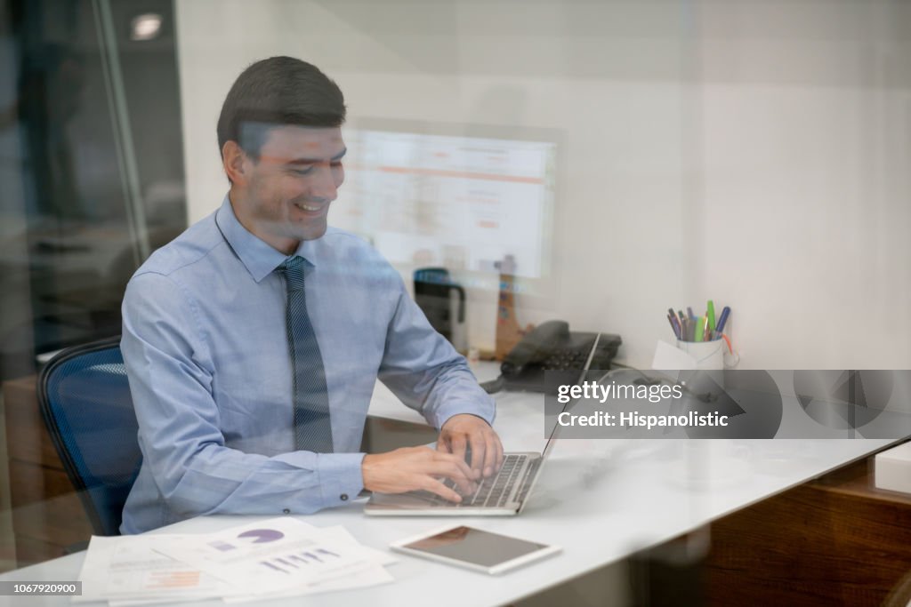 Jovem empresário, trabalhando no escritório no laptop olhando muito feliz