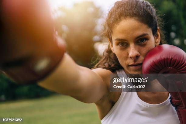 junge frau praktizierender boxe im freien - woman fighter stock-fotos und bilder