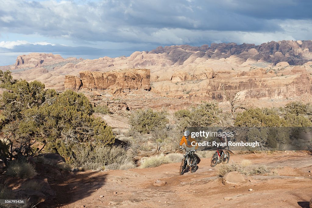 Two young men ride their bikes across the slickrock on the Amasa Back Trail in Moab, UT.