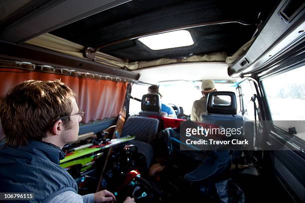 three men riding in a classic van with ski equipment everywhere. - classic car point of view stock-fotos und bilder