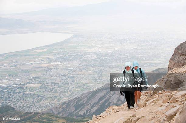 two female hikers near the summit of mt. timpanogos, with the city of pleasant grove, ut in the background. - mt timpanogos stock pictures, royalty-free photos & images