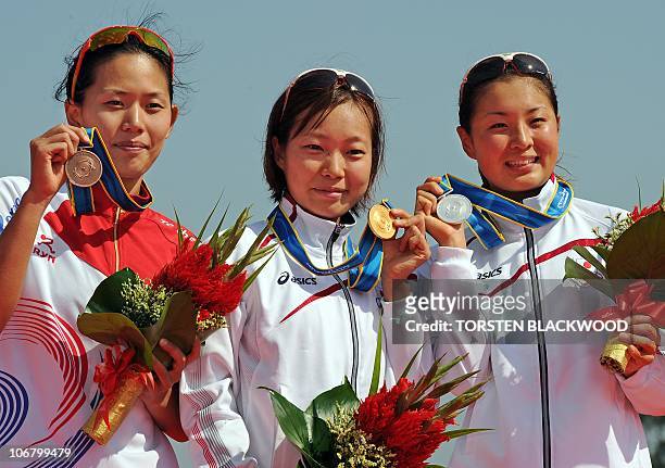 Gold medalist Mariko Adachi of Japan poses on the podium with fellow silver medalist Akane Tsuchihashi and bronze medalist Jang Yun Jung of South...