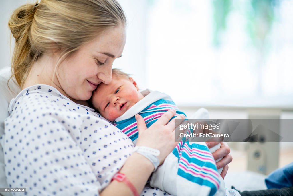 New mom holds her baby in hospital bed