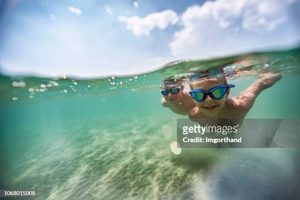 little boys enjoying swimming underwater in sea - boy swimming stock pictures, royalty-free photos & images