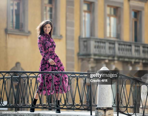 fashion model with a candid smile on a bridge in venice, italy - floral dress stock pictures, royalty-free photos & images