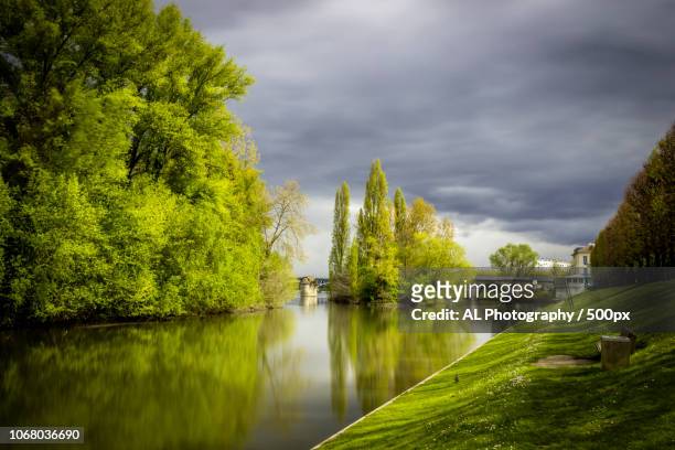 water canal with trees and storm clouds in background - yvelines stock-fotos und bilder