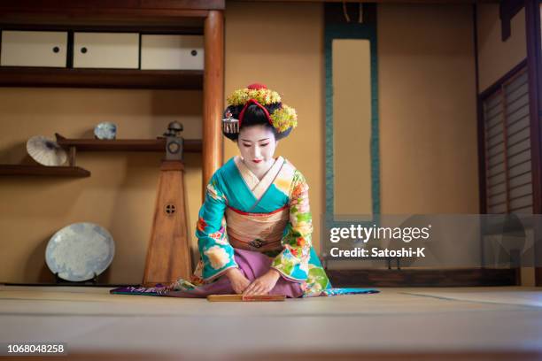 maiko girl sitting on heels and bowing in traditional japanese tatami room - geisha japan stock pictures, royalty-free photos & images