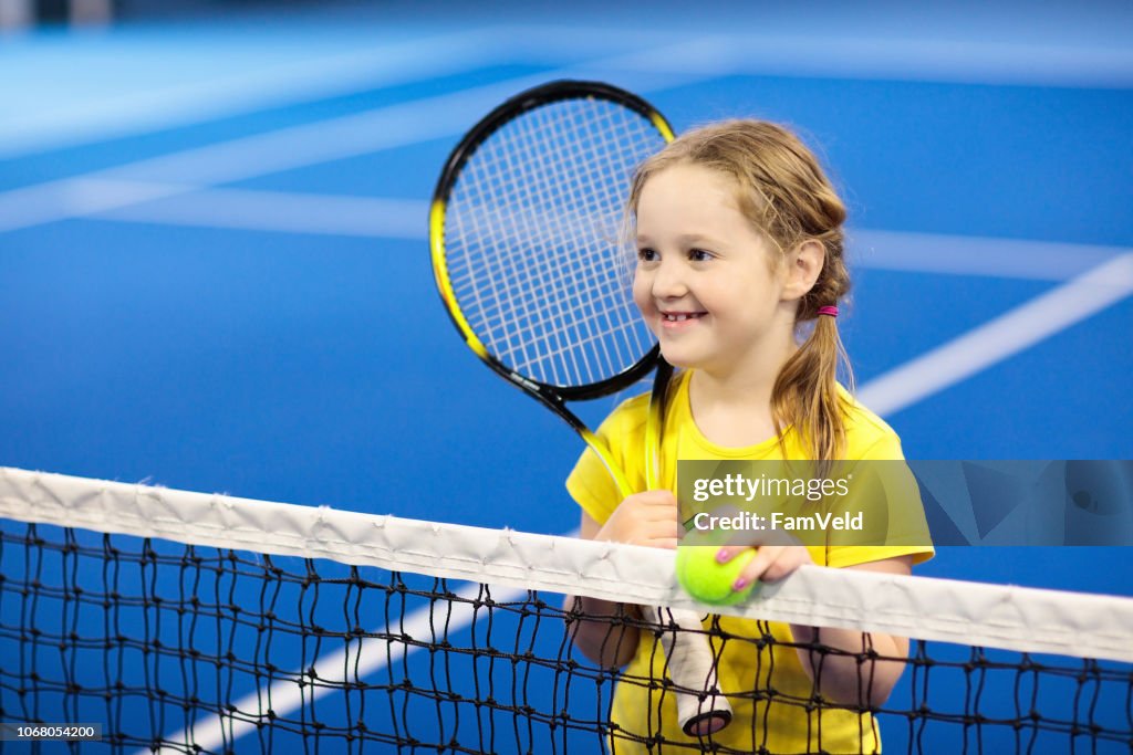 Niño jugando tenis en cancha cubierta