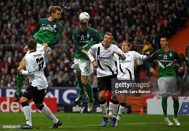 Per Mertesacker and Sebastian Proedl of Bremen go up for a header with Maik Franz of Frankfurt during the Bundesliga match between SV Werder Bremen...
