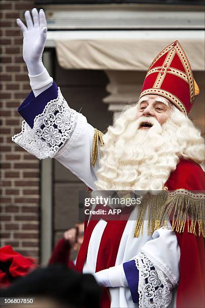 Man dressed as Sinterklaas, or Saint Nicholas, waves to children after his arrival by boat in the harbour of Hardewijk on November 13, 2010. The...