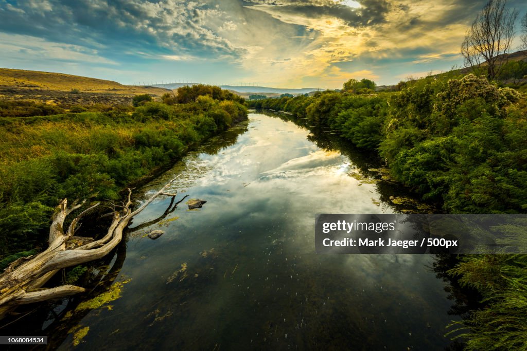 Stream running through landscape at dusk