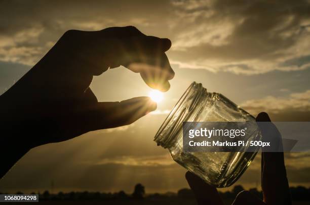 person holding jar against sunny sky - perspective artificielle photos et images de collection