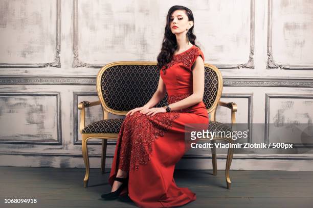 portrait of young woman wearing red evening gown - evening gown stock-fotos und bilder