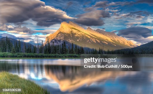 Shiny lake with mountains illuminated by setting sun in background Shiny lake with mountains illuminated by setting sun in background