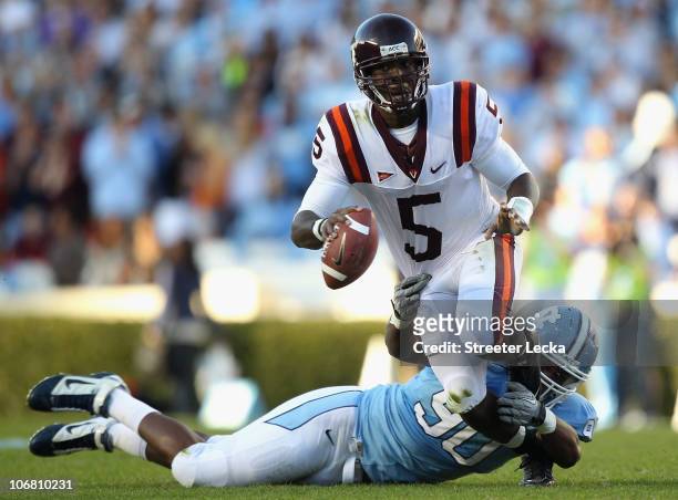 Tyrod Taylor of the Virginia Tech Hokies tries to get away from Quinton Coples of the North Carolina Tar Heels during their game at Kenan Stadium on...