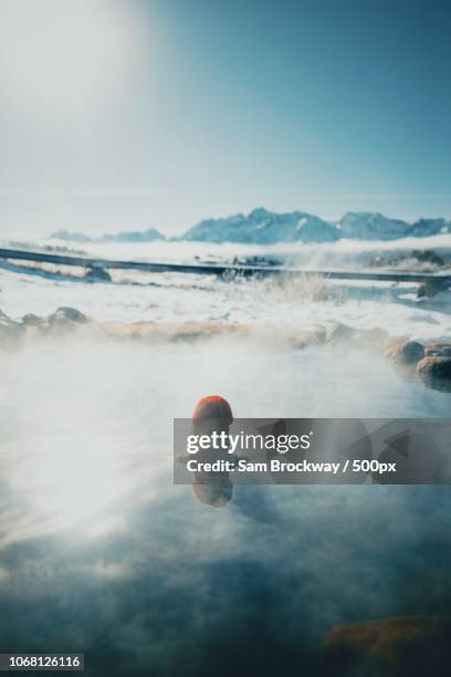 woman bathing in hot spring, sawtooth range in background, stanley, idaho, usa - thermalquelle stock-fotos und bilder