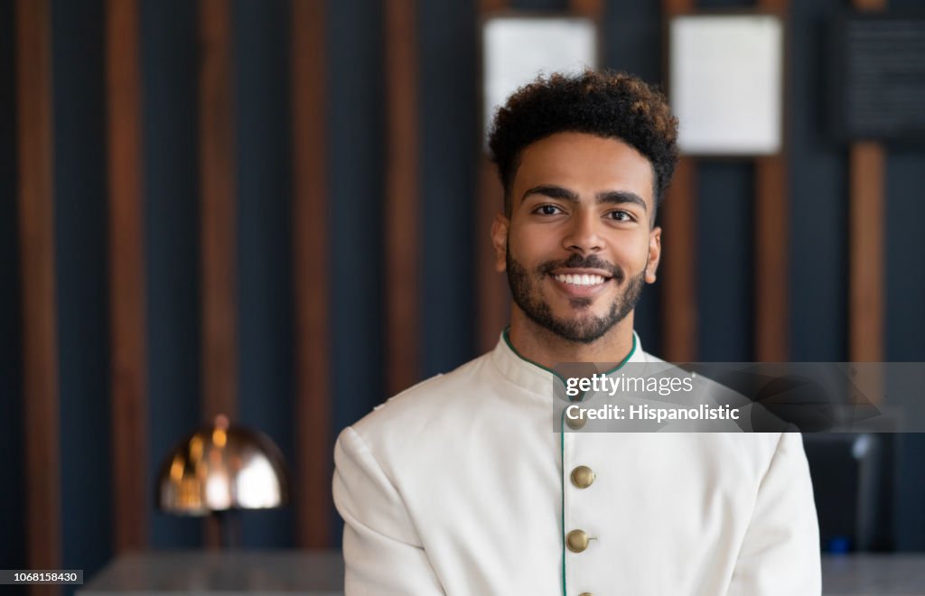 Retrato de negro paquete amigável trabalhando no hotel olhando para câmera muito feliz