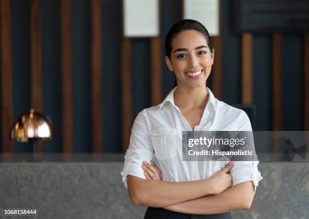 vertrouwen latijns-amerikaanse hotelmanager kijken camera glimlachen met armen gekruist - concierge stockfoto's en -beelden