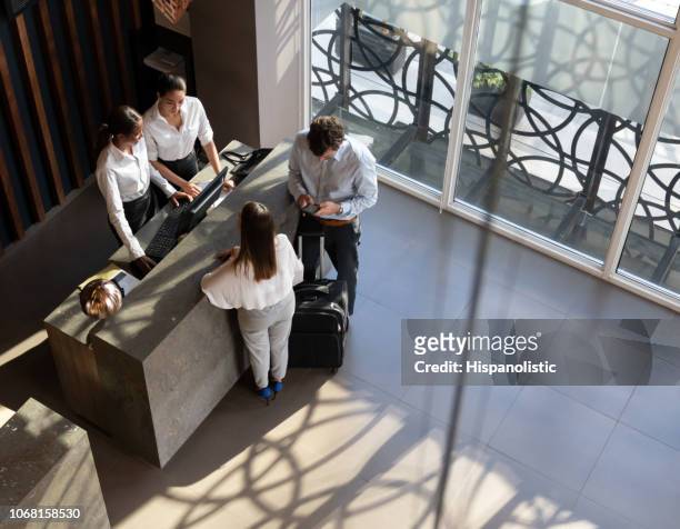 black manager and recepcionist checking in a couple and man looking at his smartphone - study hall stock pictures, royalty-free photos & images