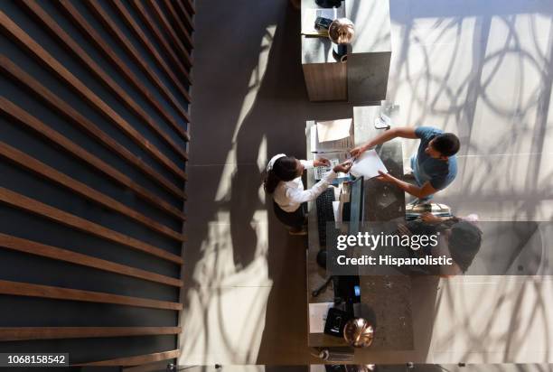 agradable recepcionista negro da forma a la huésped masculino comprobando con la pareja en un hotel de lujo - conserje fotografías e imágenes de stock
