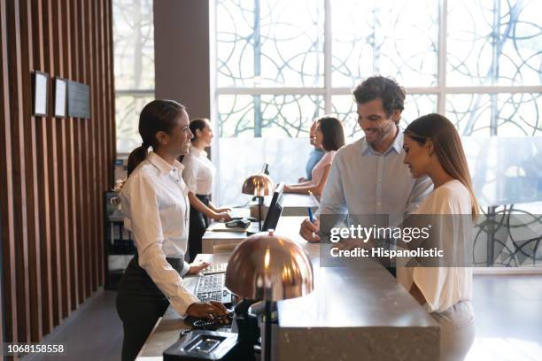 mensen in een hotel genieten van hun vakantie controleren bij het invullen van een formulier - reception stockfoto's en -beelden