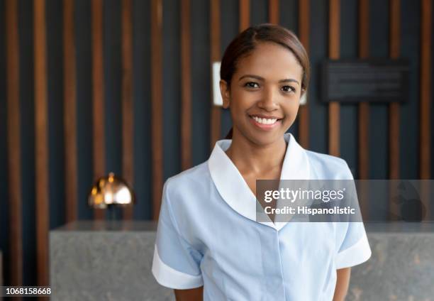 beautiful black chambermaid at the hotel lobby looking at camera smiling - hotel cleaner stock pictures, royalty-free photos & images