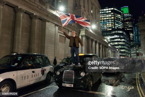 John McDonnell, taxi driver waiving an UK flag on top of a black cab. Dozens of black cab taxi drivers together with their cabs protest against the...