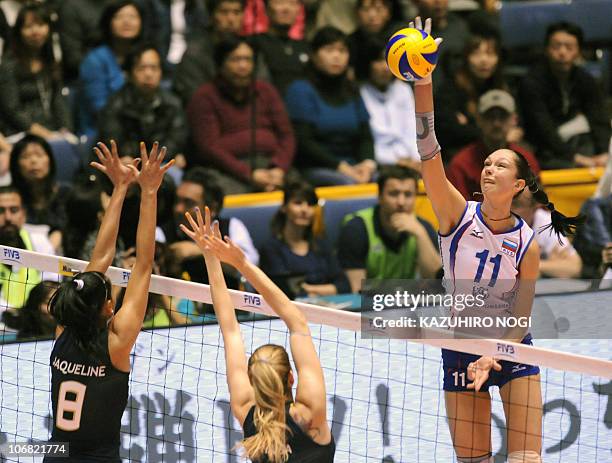 Russian attacker Ekaterina Gamova spikes the ball over Brazil's Jaqueline Carvalho and Thaisa Menezes during their final match against Russian at the...