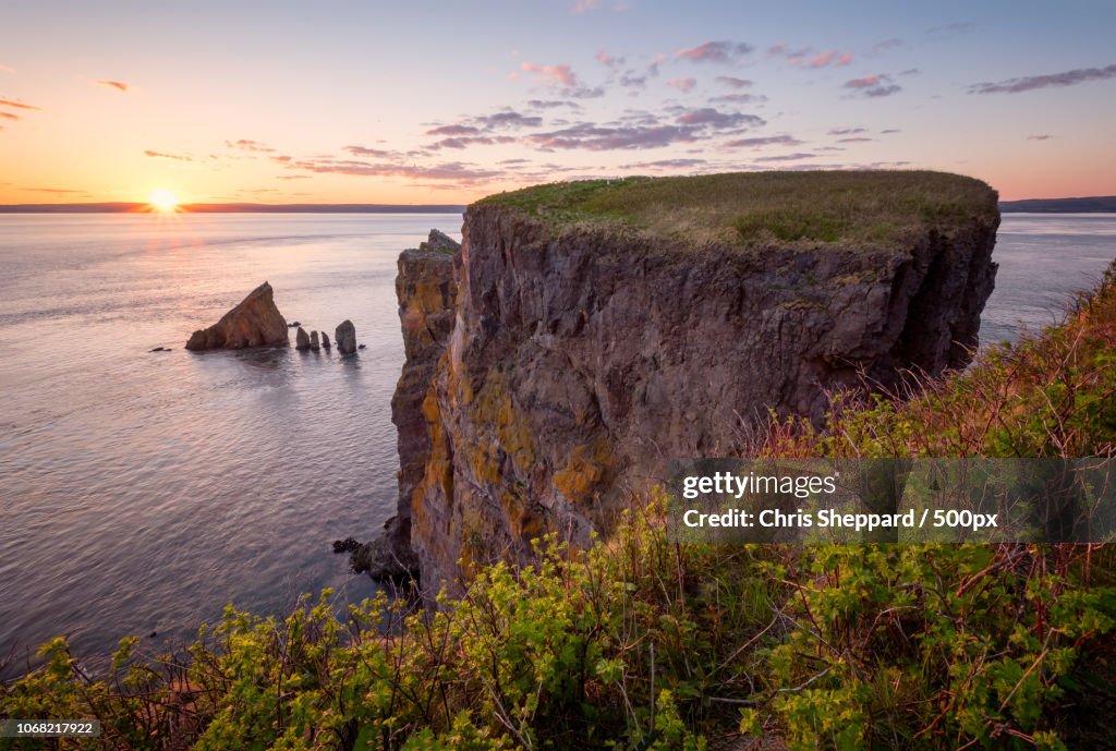 View of rock formation with cliffs on seashore at sunset