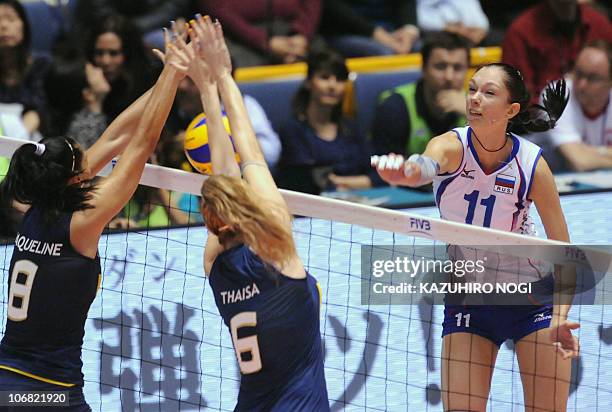 Russian attacker Ekaterina Gamova spikes the ball against Brazil's Jaqueline Carvalho and Thaisa Menezes during their final match against Russia at...