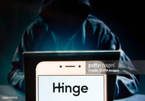In this photo illustration, the Online dating app Hinge logo is seen displayed on an Android mobile device with a figure of hacker in the background.